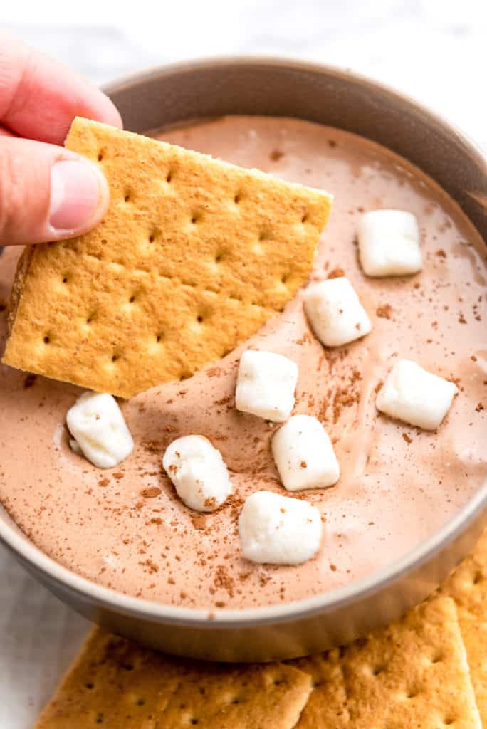 graham cracker being dipped into hot chocolate dessert dip