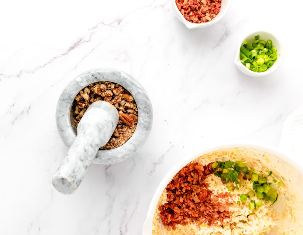 using a mortar and pestle to chop up pecans for bacon pecan cheese ball