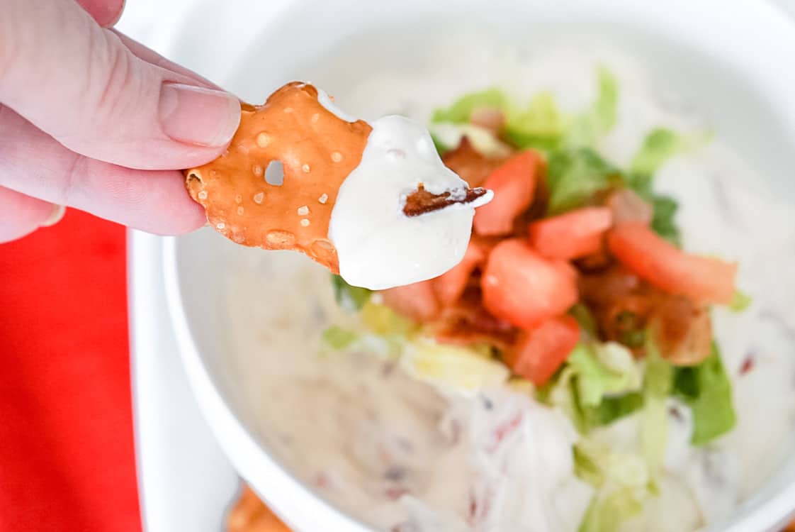 a pretzel crisp being dipped into blt dip
