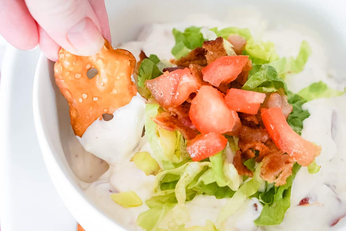 a pretzel crisp being dipped into blt dip