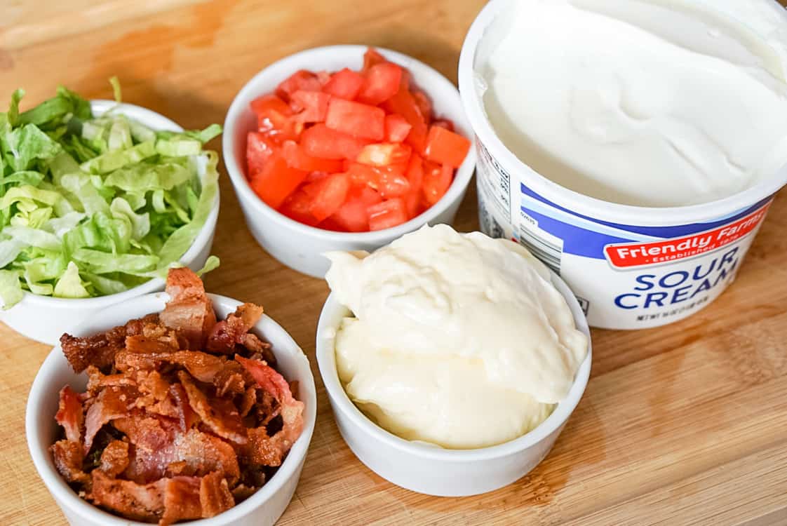 portioned ingredients for blt dip recipe including bacon lettuce tomato mayo and sour cream