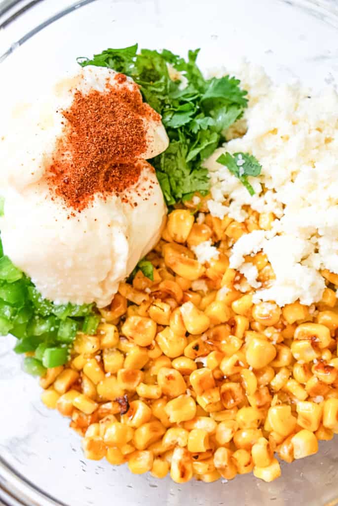 elote dip ingredients in a clear glass bowl