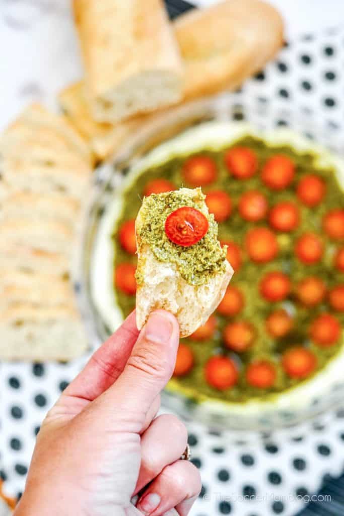 woman holding a baguette with hot caprese dip
