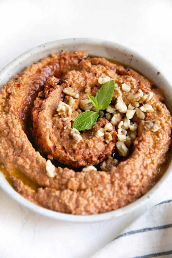 Muhammara red pepper and walnut dip prepared in a white bowl