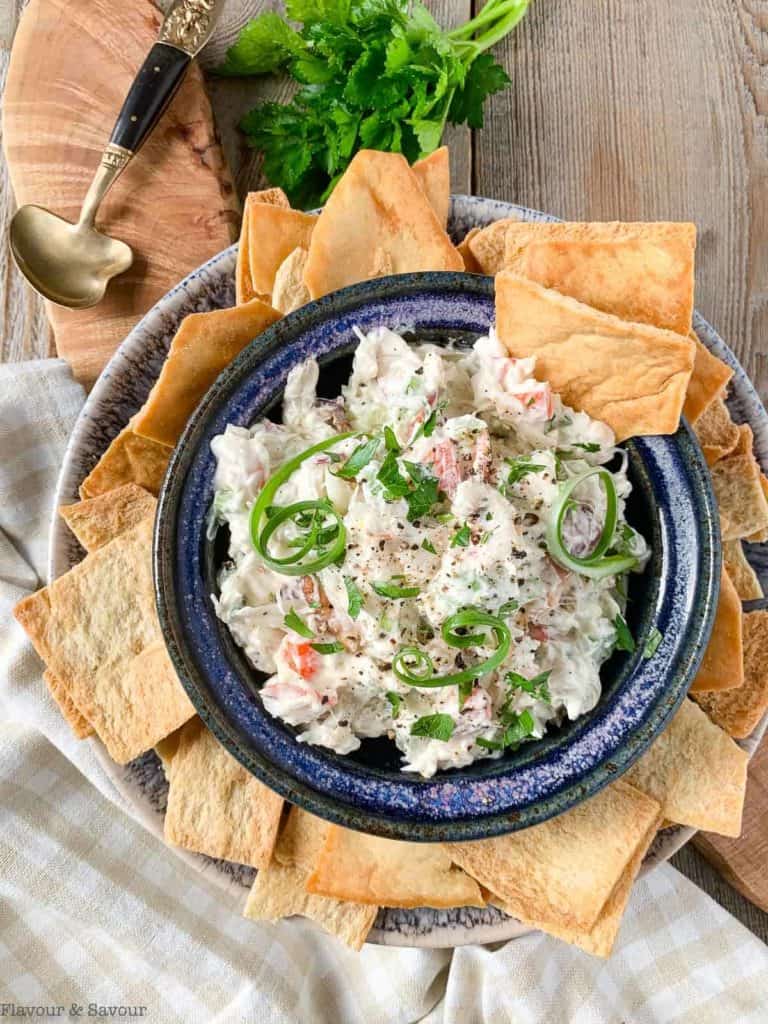 cold crab dip in a blue bowl with pita chip dippers on the side