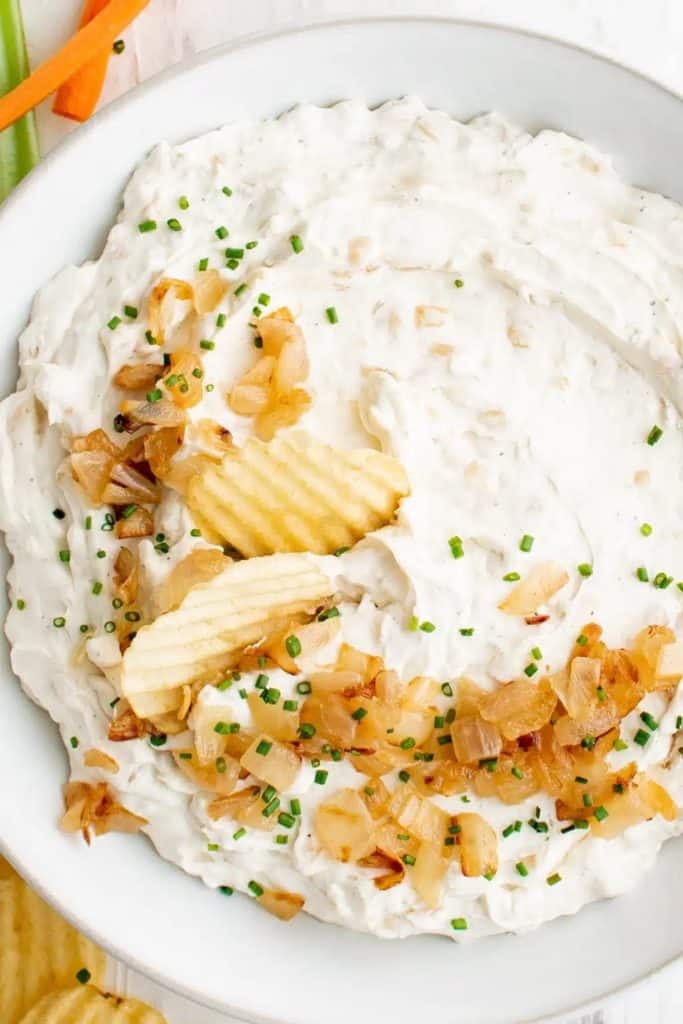 creamy prepared french onion dip with potato chips garnish 