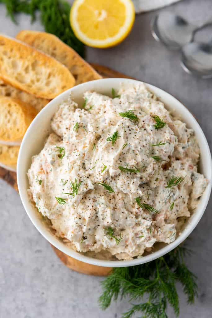 overhead photo of salmon cream cheese dip with dill garnish and sliced baguette on the side