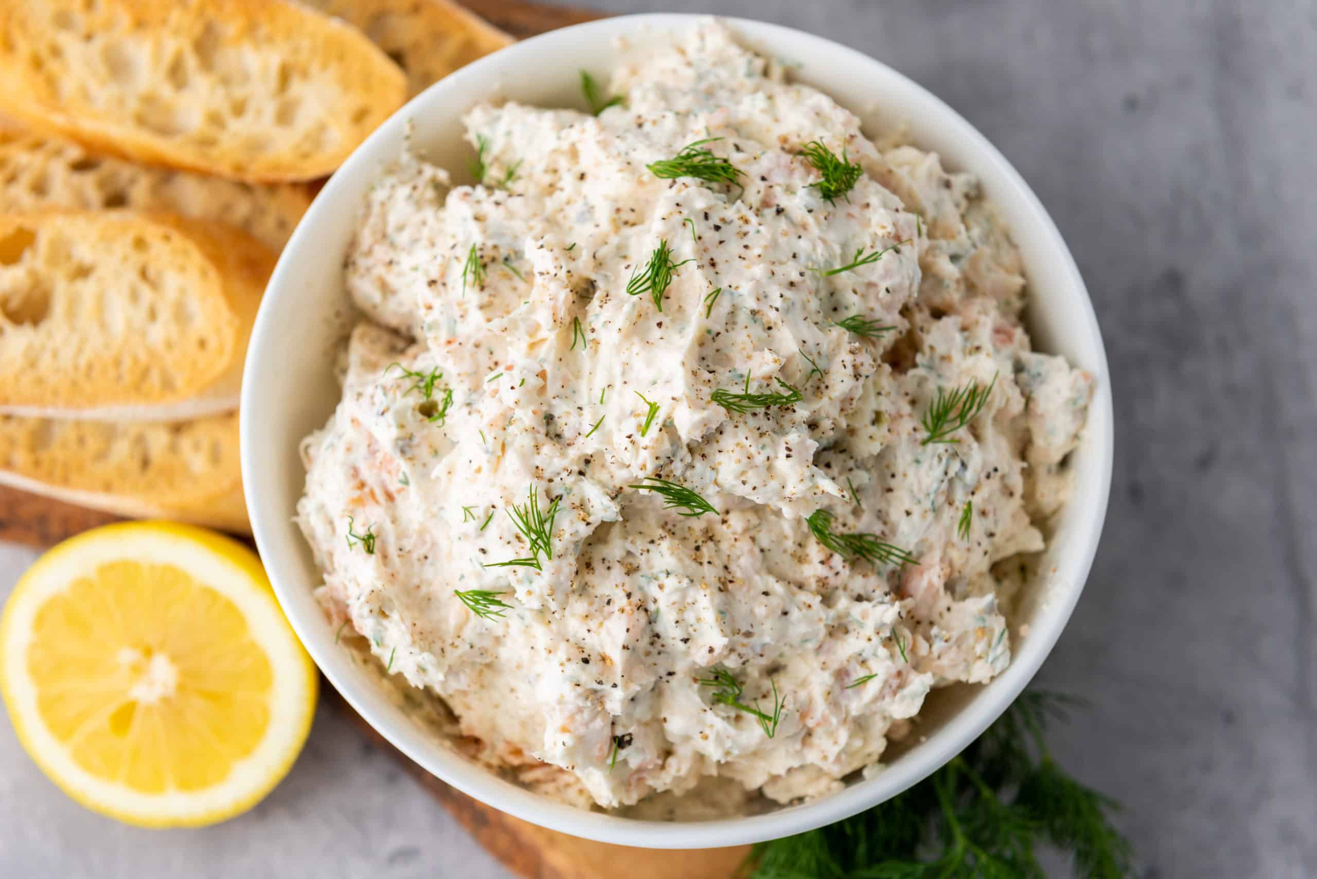 smoked salmon cream cheese dip in a bowl with sliced baguette on the side