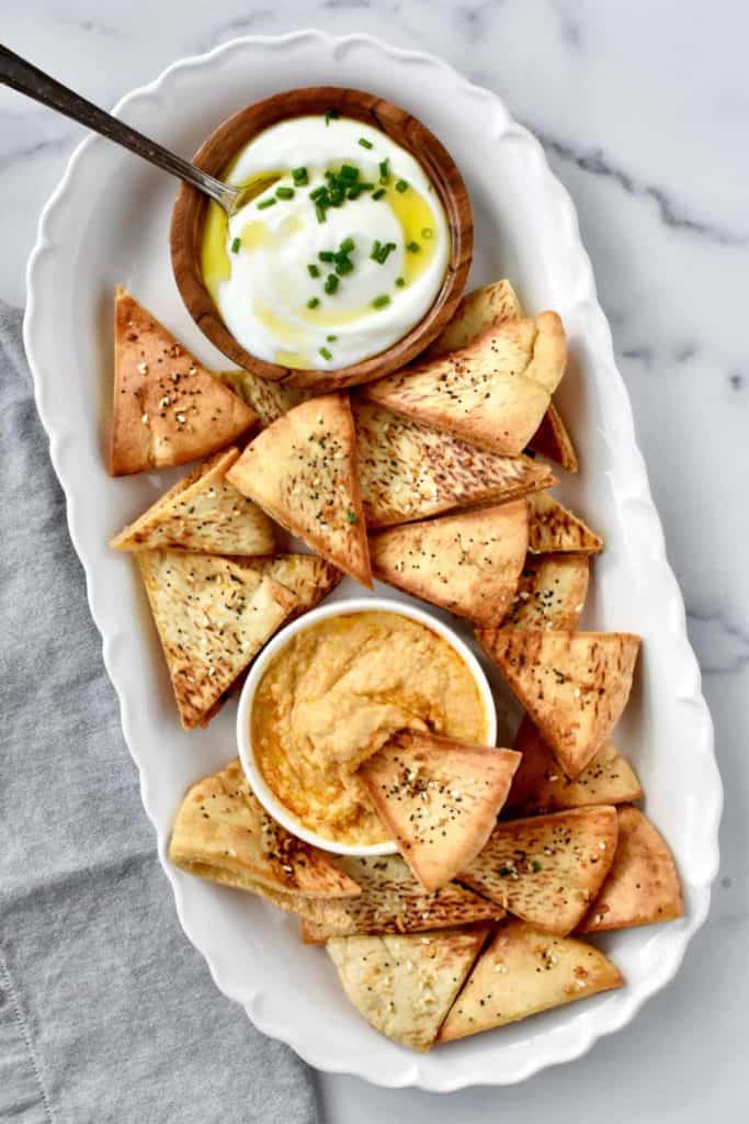 homemade air fryer pita chips in a white dish with two dips on the side