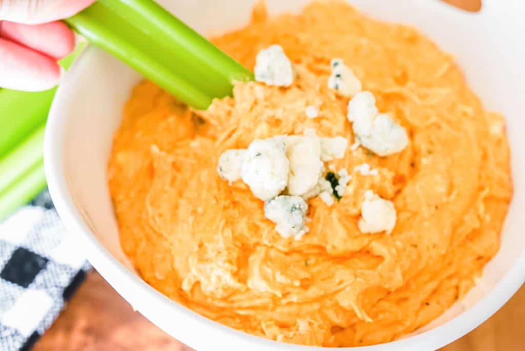 celery stick being dipped in franks red hot buffalo chicken dip
