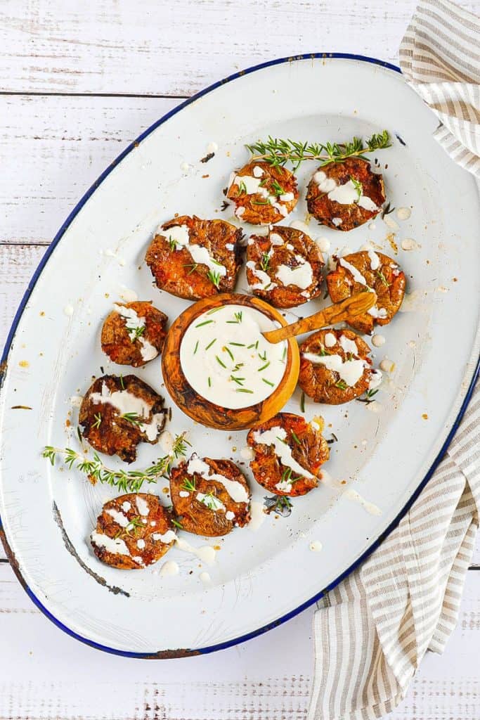 crispy smashed potatoes on a plate with aioli drizzle. 