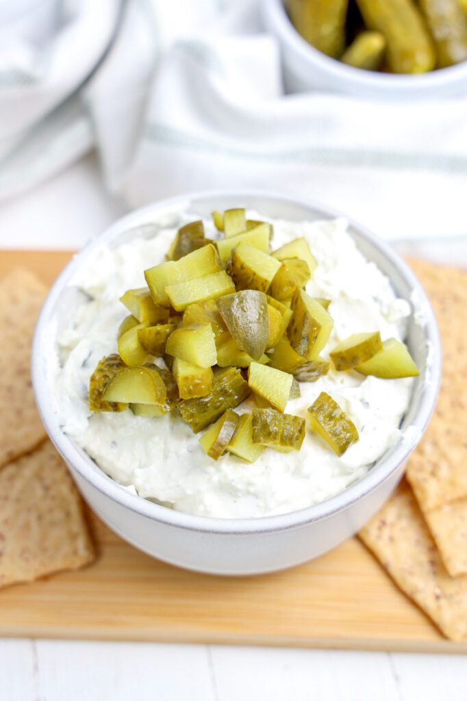 dill pickle dip in a white bowl with chips