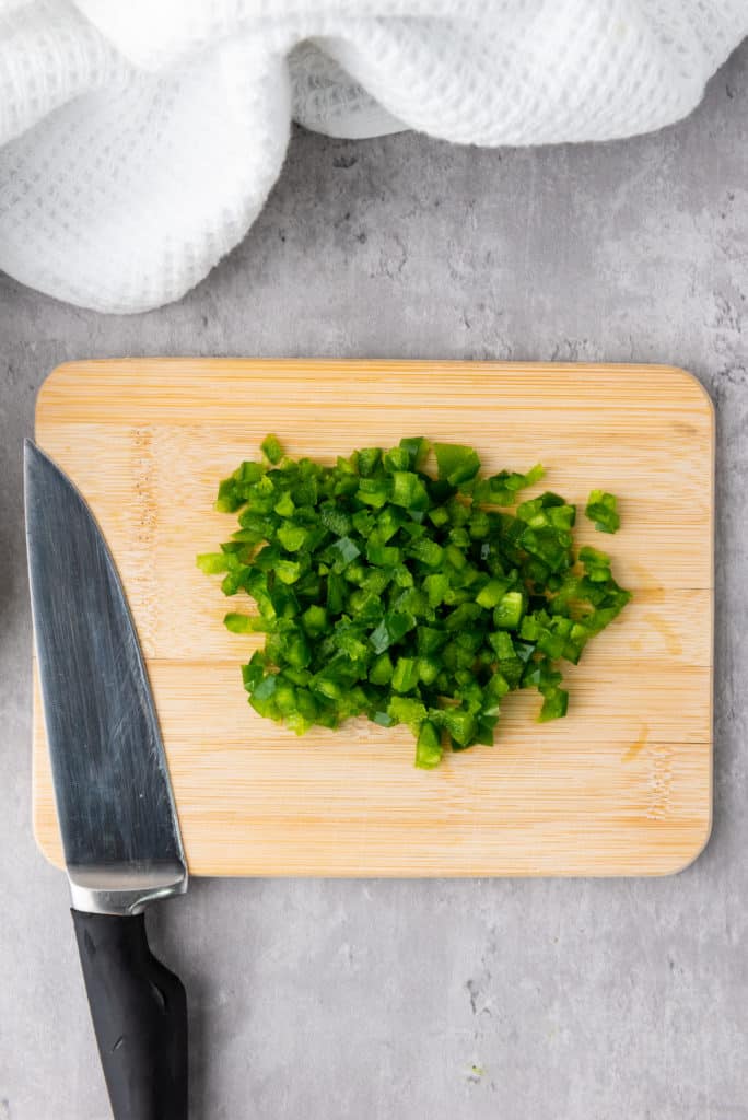 chopped jalapeno pepper on a wood cutting board
