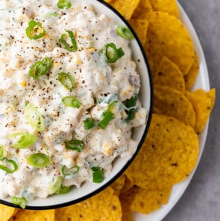 overhead shot of corn dip in a bowl surrounded by tortilla chipis