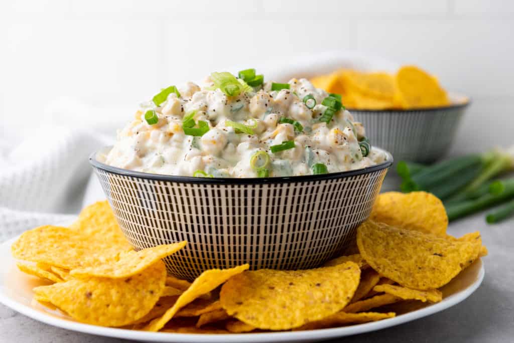 side view of corn dip in a decorative bowl with corn chips on the side