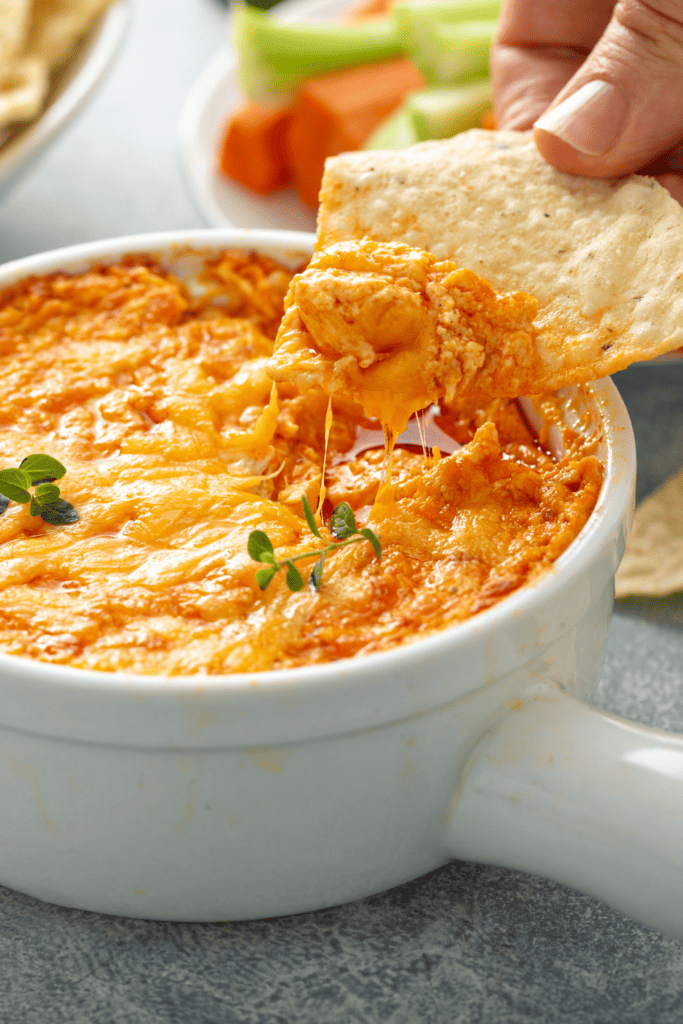 tortilla chip being dipped in buffalo chicken dip