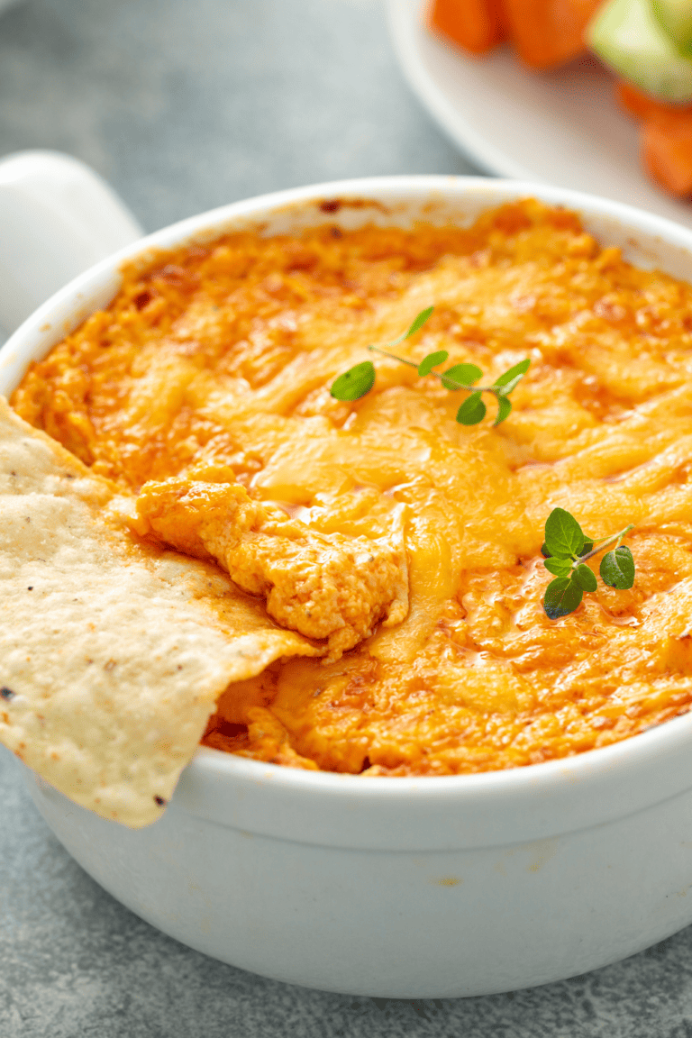 tasty buffalo chicken dip in a white bowl with a tortilla chip