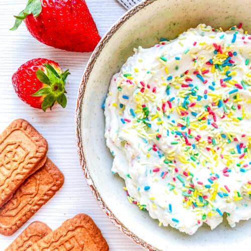 funfetti dip in a white bowl with strawberries and cookies for dipping