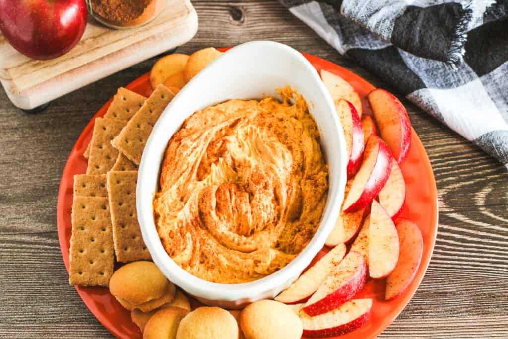 pumpkin cream cheese dip surrounded by apple slices, vanilla wafers and graham crackers