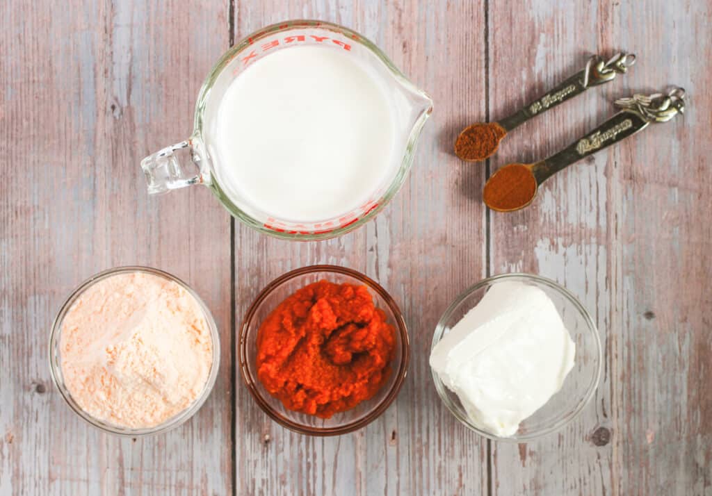 ingredients for pumpkin cream cheese dip, including pumpkin, instant pudding, heavy cream, cream cheese, cinnamon and nutmeg