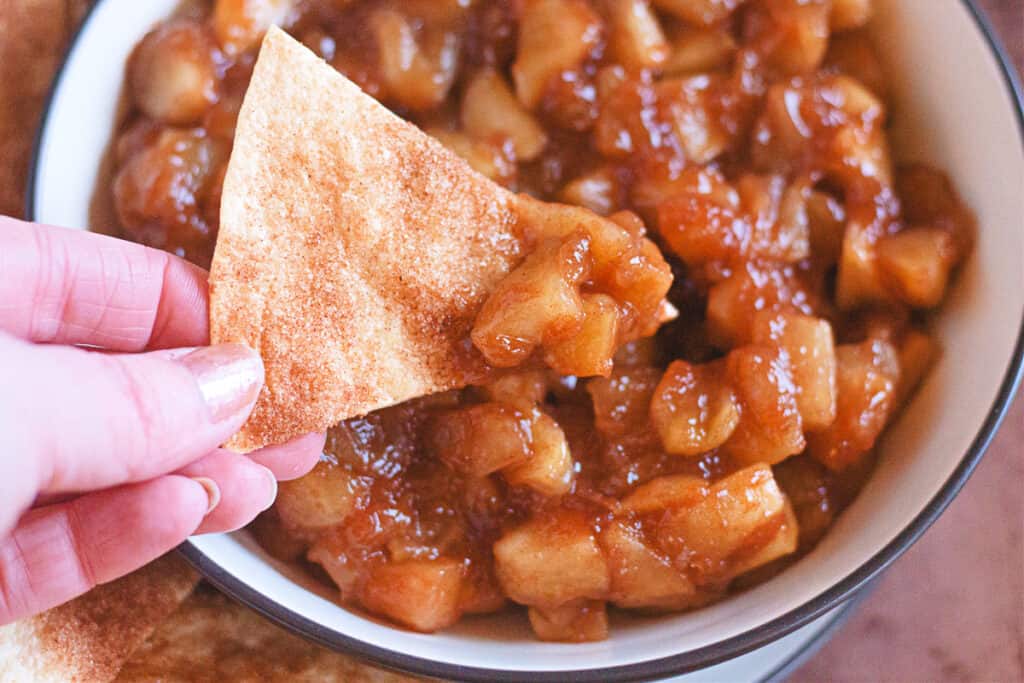 cinnamon sugar tortilla chips being dipped in warm apple pie dip