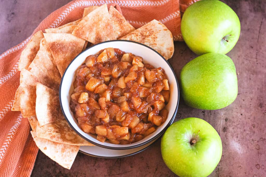warm apple pie dip with homemade cinnamon sugar tortilla chips in a bowl