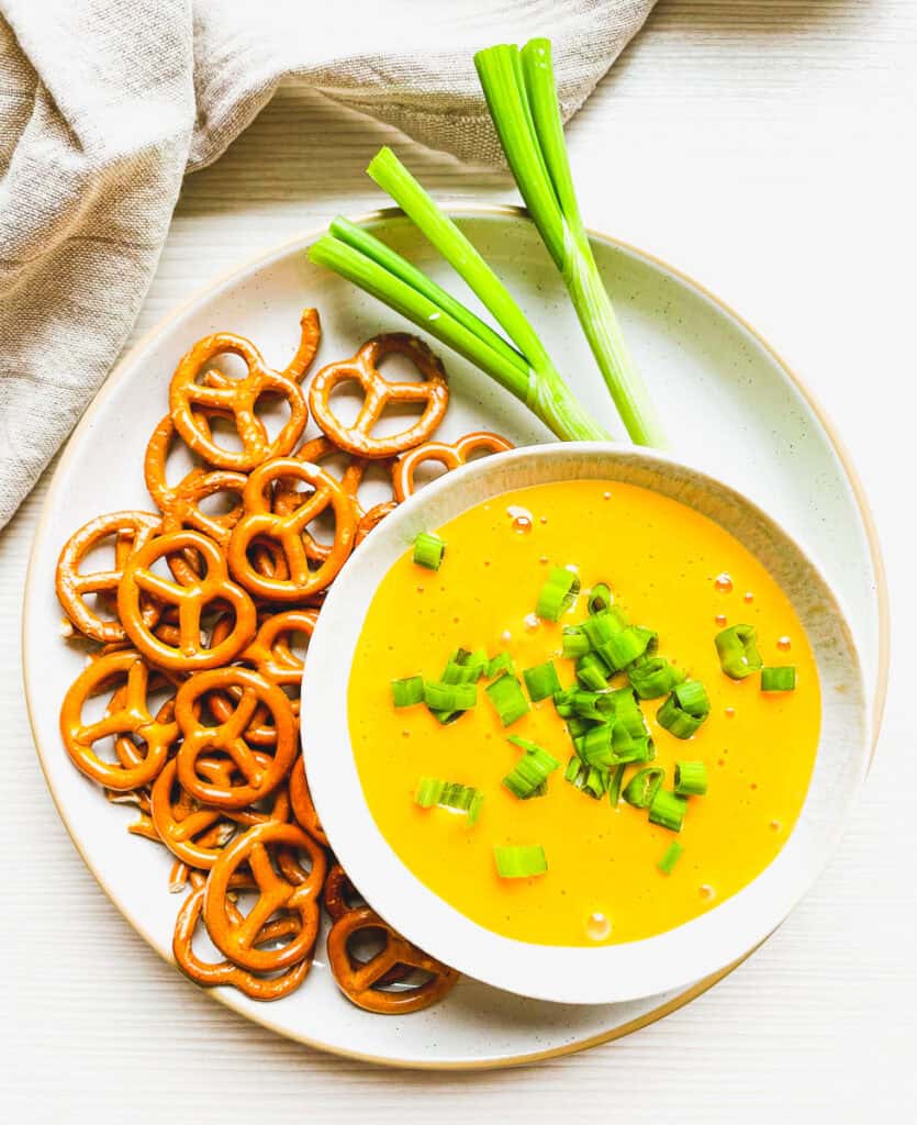 beer cheese dip with green onion garnish and pretzels on the side for dipping