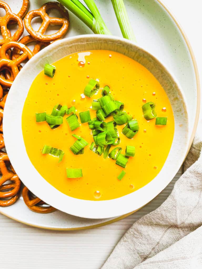 beer cheese dip for pretzels prepared in a bowl with pretzels on the side 