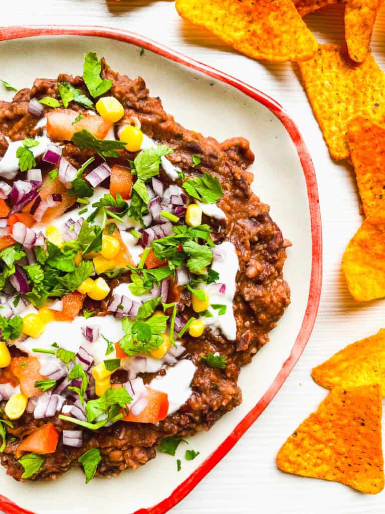 loaded black bean dip with tomatoes, corn, onions, cilantro and sour cream with Doritos on the side
