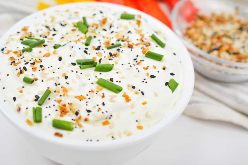 Bowlful of everything bagel dip topped with chives and everything bagel seasoning