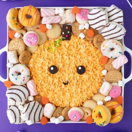 complete halloween pumpkin frosting board surrounded by cookies and cakes on a purple background