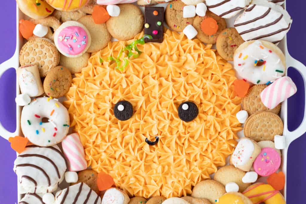 the cutest halloween frosting dessert board in the shape of a pumpkin with sweet dippers on the side