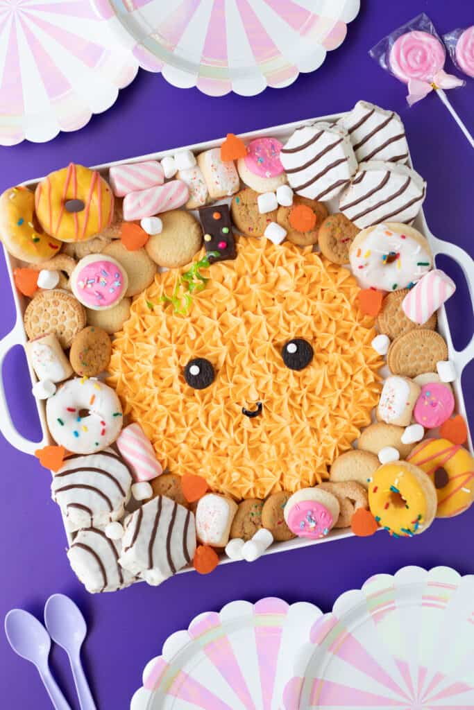 the most adorable Halloween pumpkin frosting board surrounded by donuts, cookies and cakes 