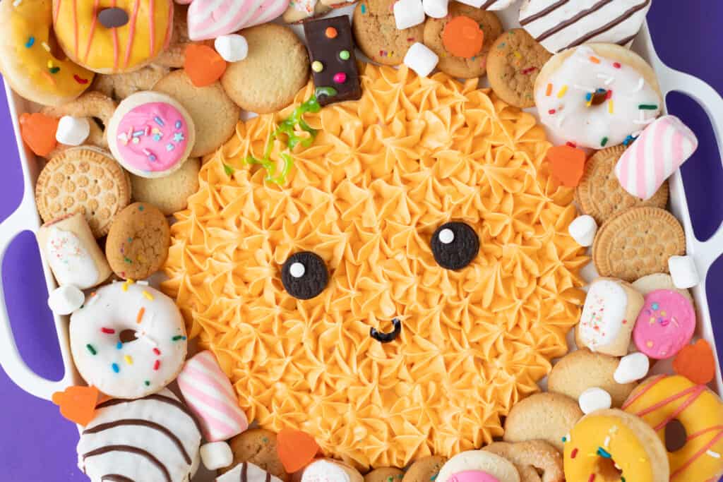 halloween themed frosting board surrounded by cakes and cookies