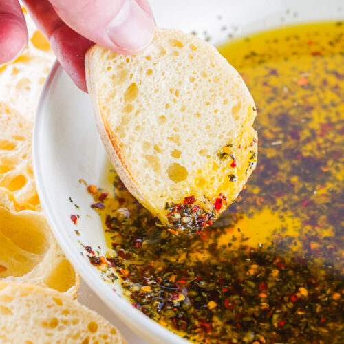 baguette slide being dipped in homemade bread dipping oil