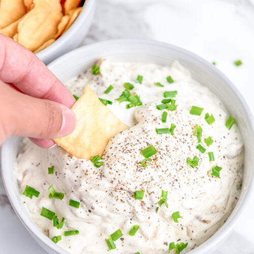 prepared caramelized onion dip with a pita chip being dipped