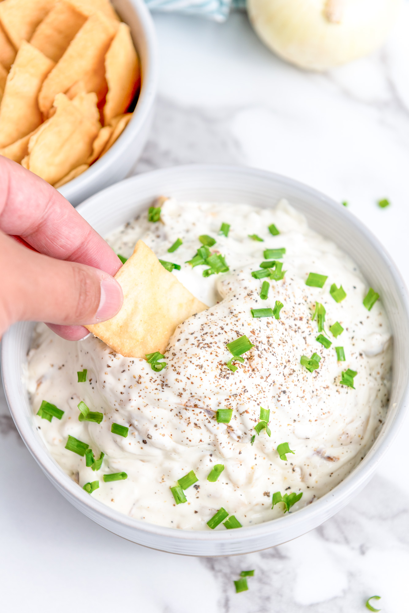 prepared caramelized onion dip with a pita chip being dipped