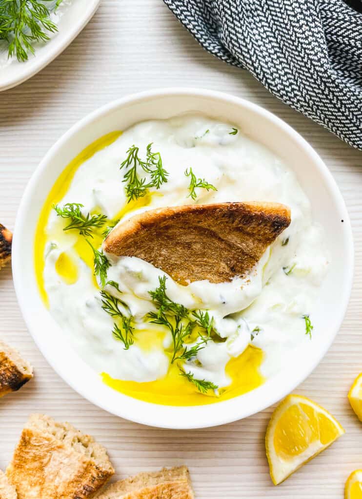 ready to serve homemade tzatziki made with sour cream and drizzled with olive oil and garnished with fresh dill