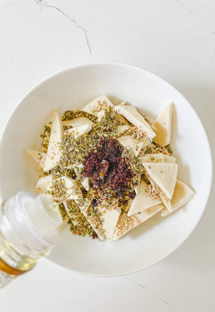 pita bread triangles being tossed in Zaatar spices and olive oil
