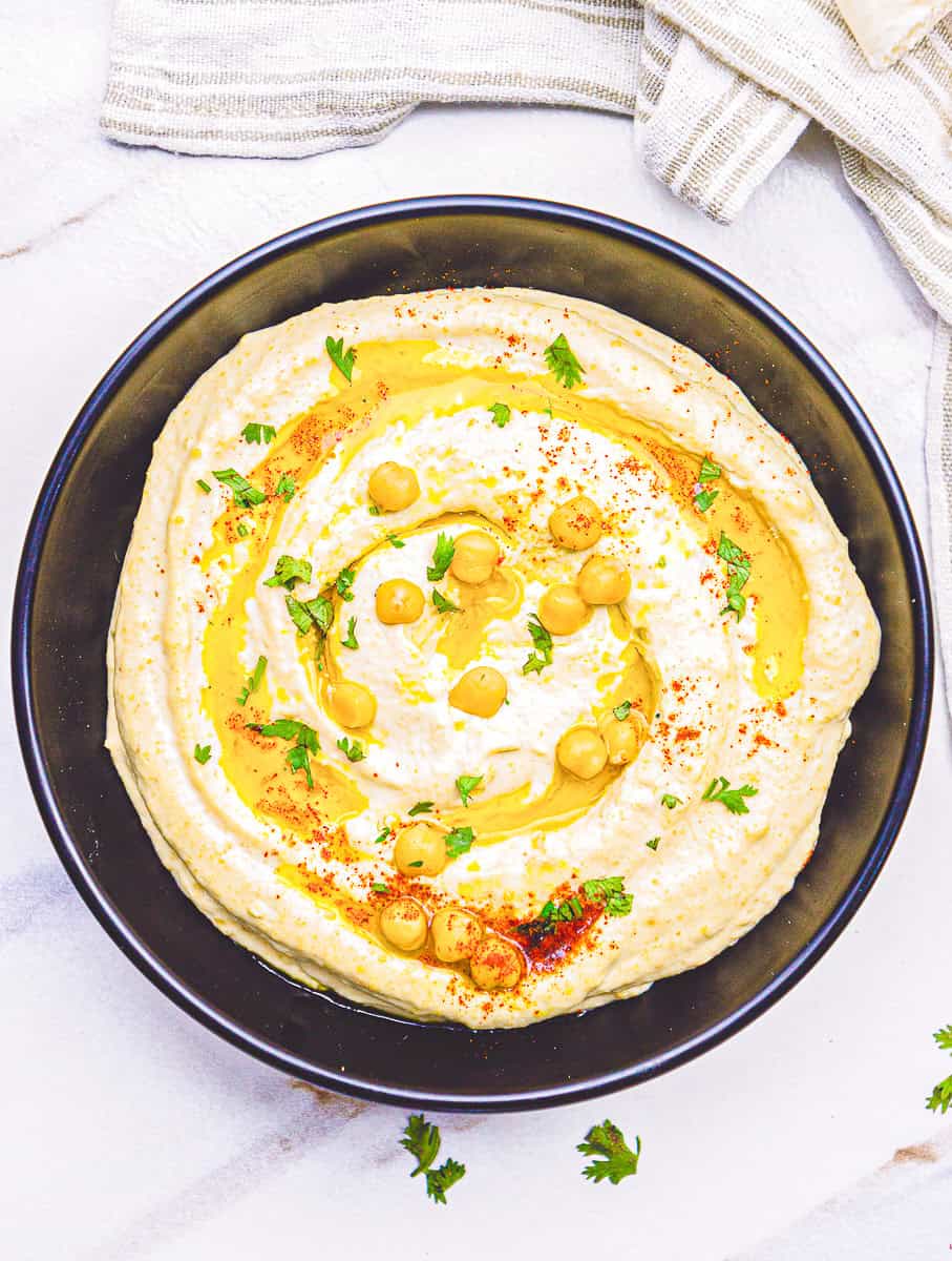authentic hummus recipe made with chickpeas tahini, olive oil and spices, prepared in a black bowl