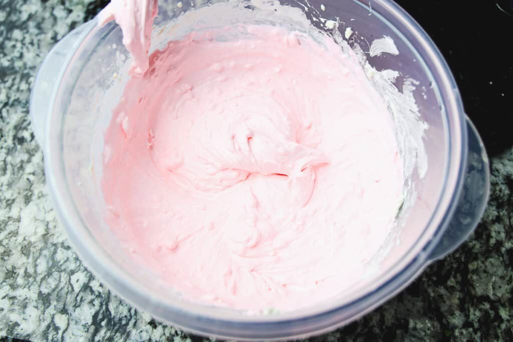 mixed cream cheese, whipped topping and pink food coloring in a bowl