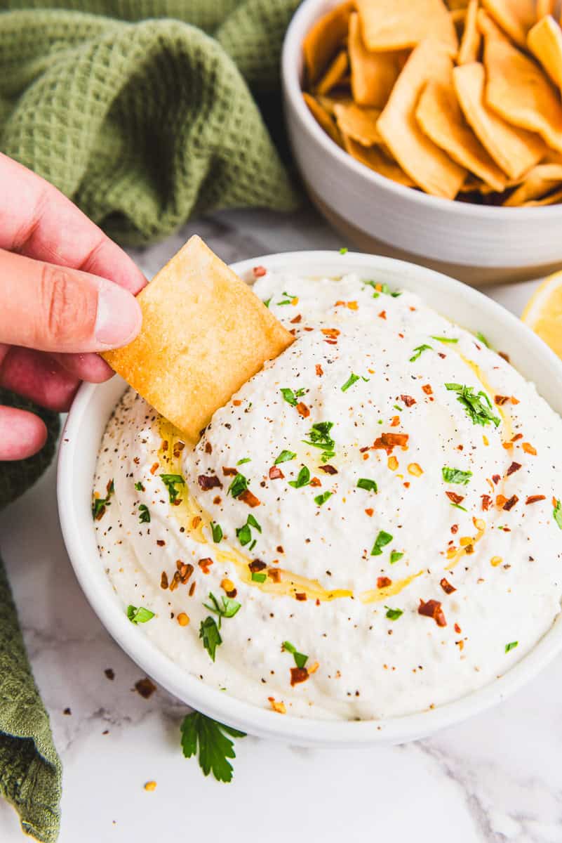 a pita chip being dipped into whipped feta