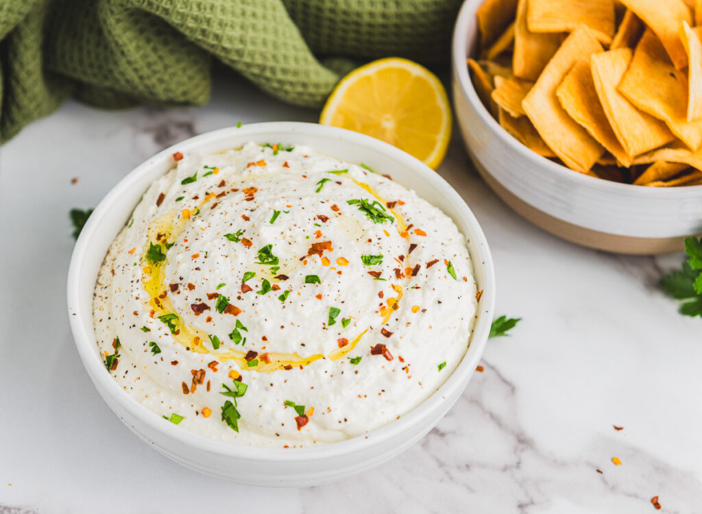 fully prepared whipped feta in a white bowl with parsley, red pepper flakes and olive oil garnish