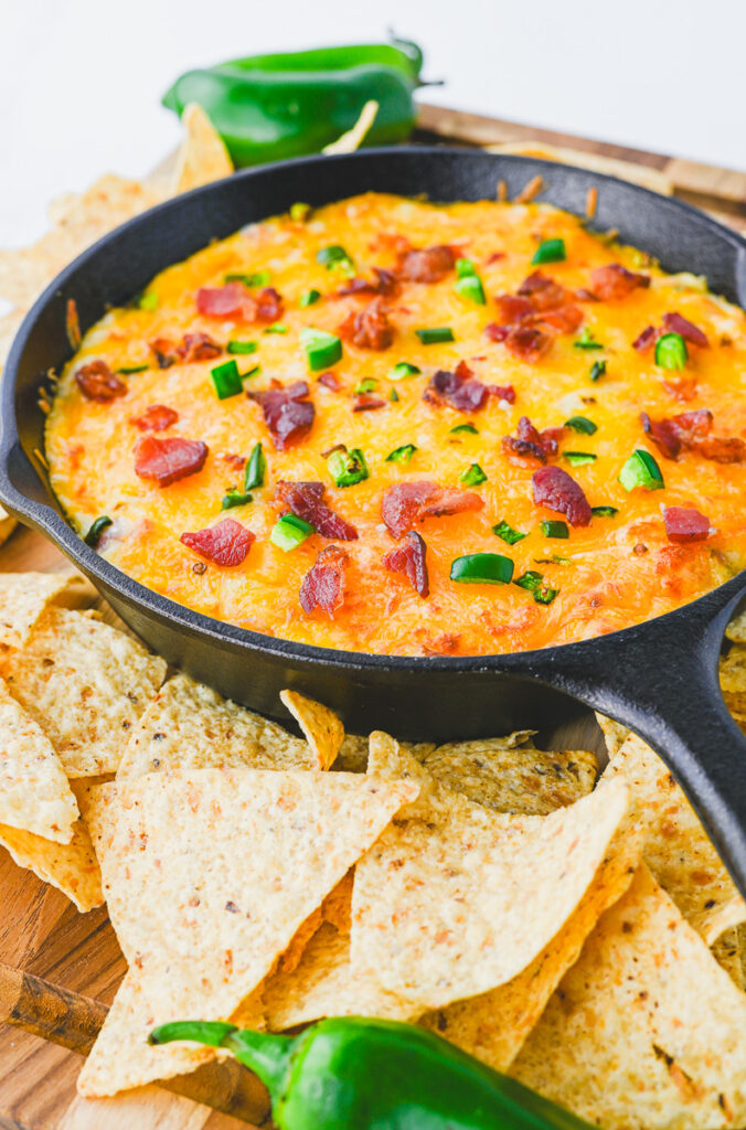 just out of the oven jalapeno dip in a cast iron skillet with a side of tortilla chips
