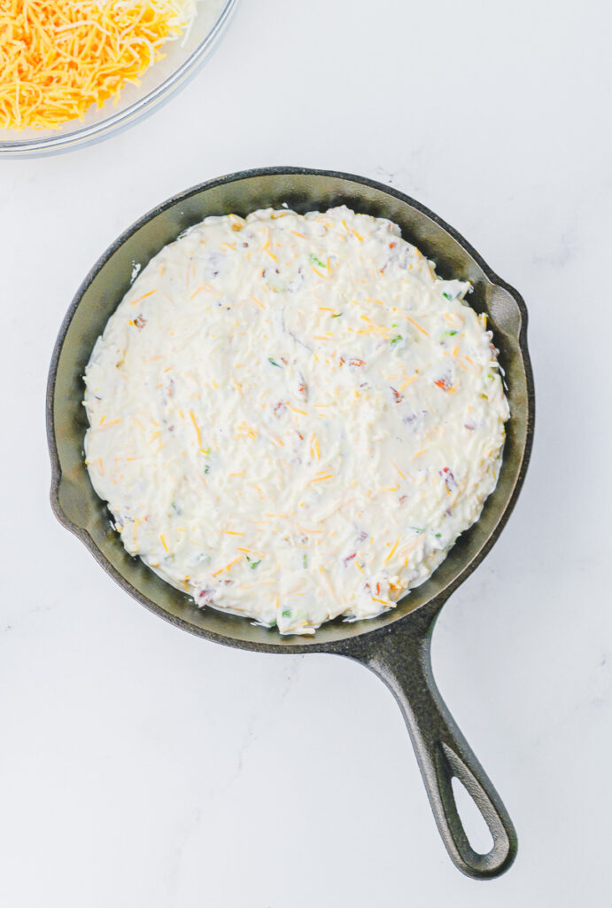 small cast iron skillet with ingredients for jalapeno popper dip readt to be put in the oven