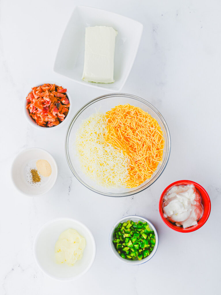 jalapeno popper dip ingredients including cream cheese, bacon, shredded cheese, sour cream, mayo, jalapenos and spices