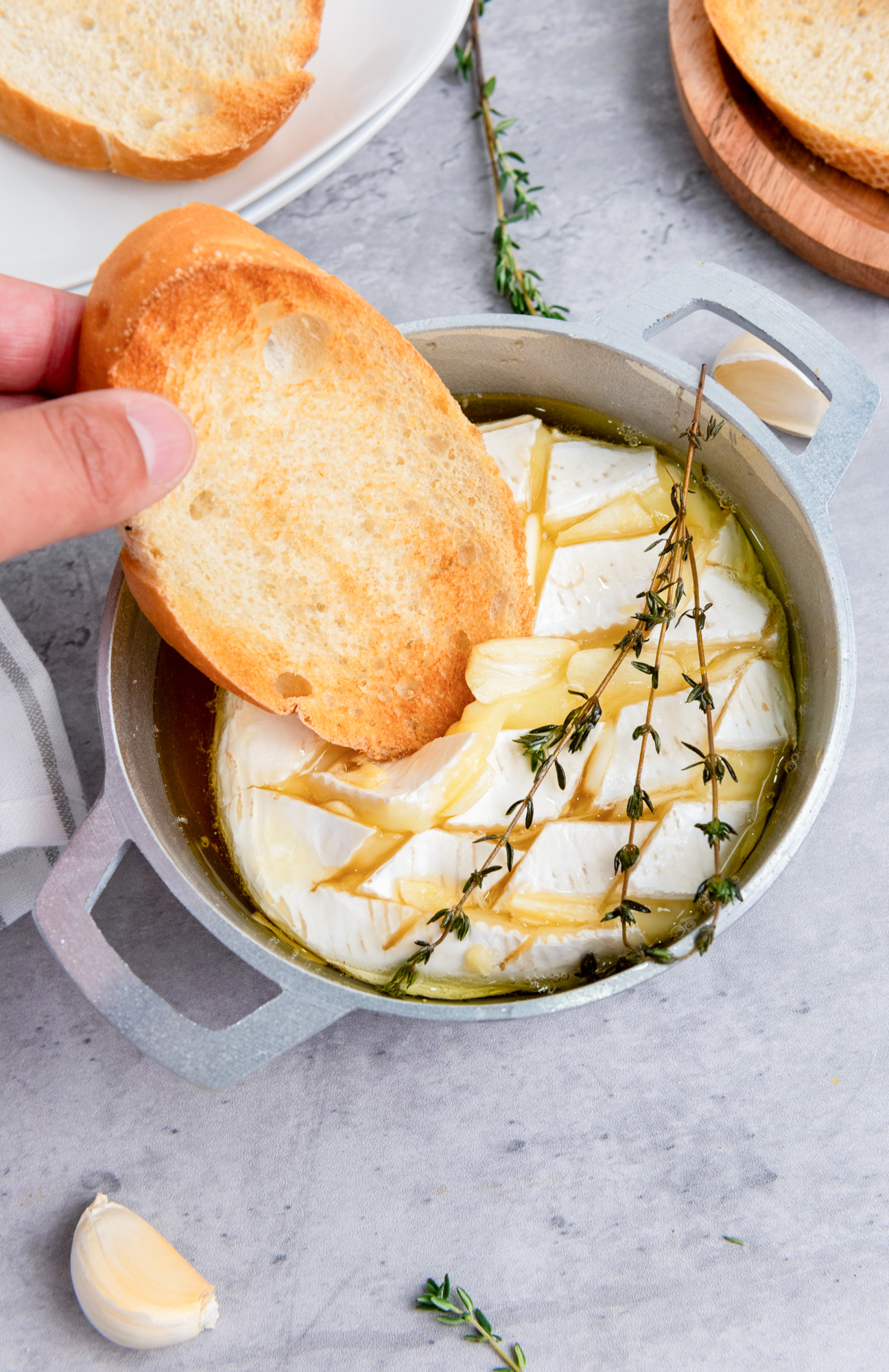 baguette being dipped into baked brie with honey