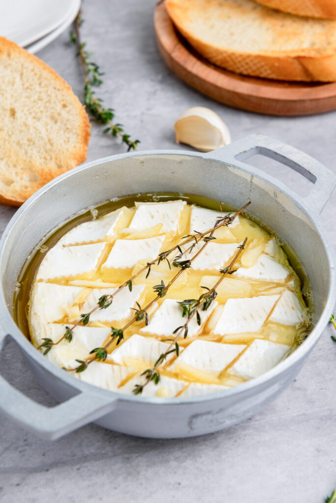 baked brie served in a brie baker with rosemary springs on top