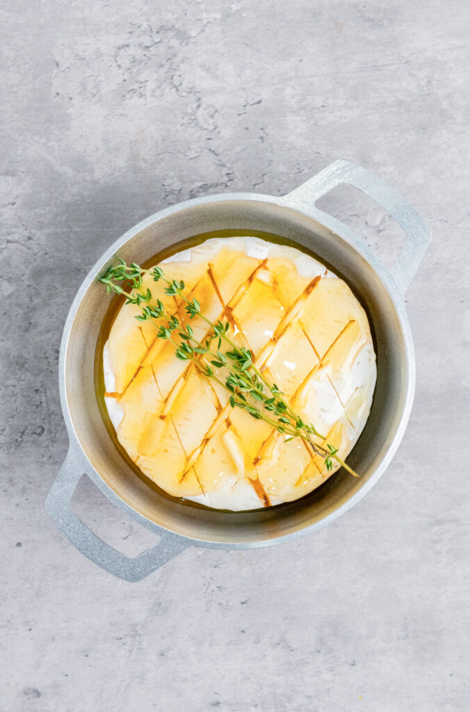 honey, olive oil and rosemary springs on top of a brie wheel