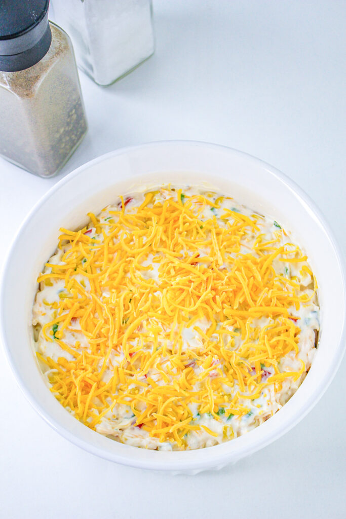 unbaked corn dip in a baking dish topped with shredded cheese